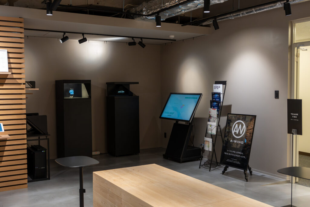 NA-T DESIGN HUB（ナッティデザインハブ）内のショールームの写真。3DCGホログラム等のデジタルコンテンツを展示する機器やタッチパネル式のコンテンツなどが設置されている。